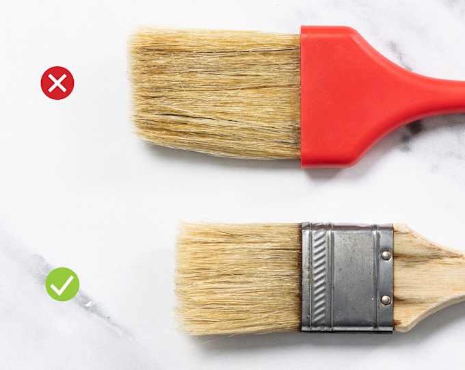 One red-handled pastry brush with very long bristles and one wood-handled pastry brush with medium bristles.